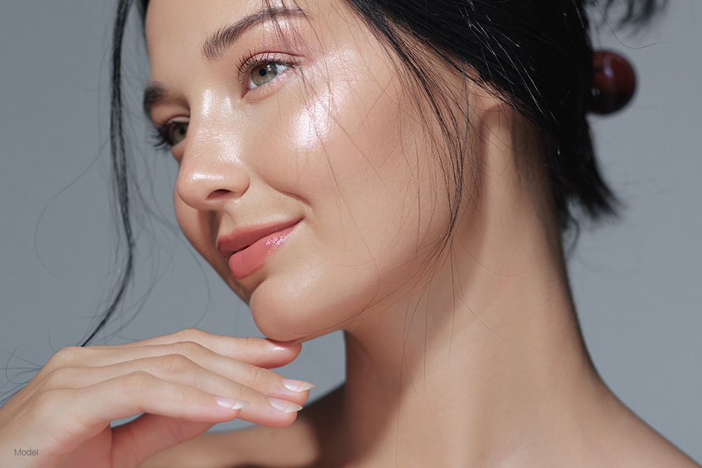 Young woman with glowing skin touching her chin